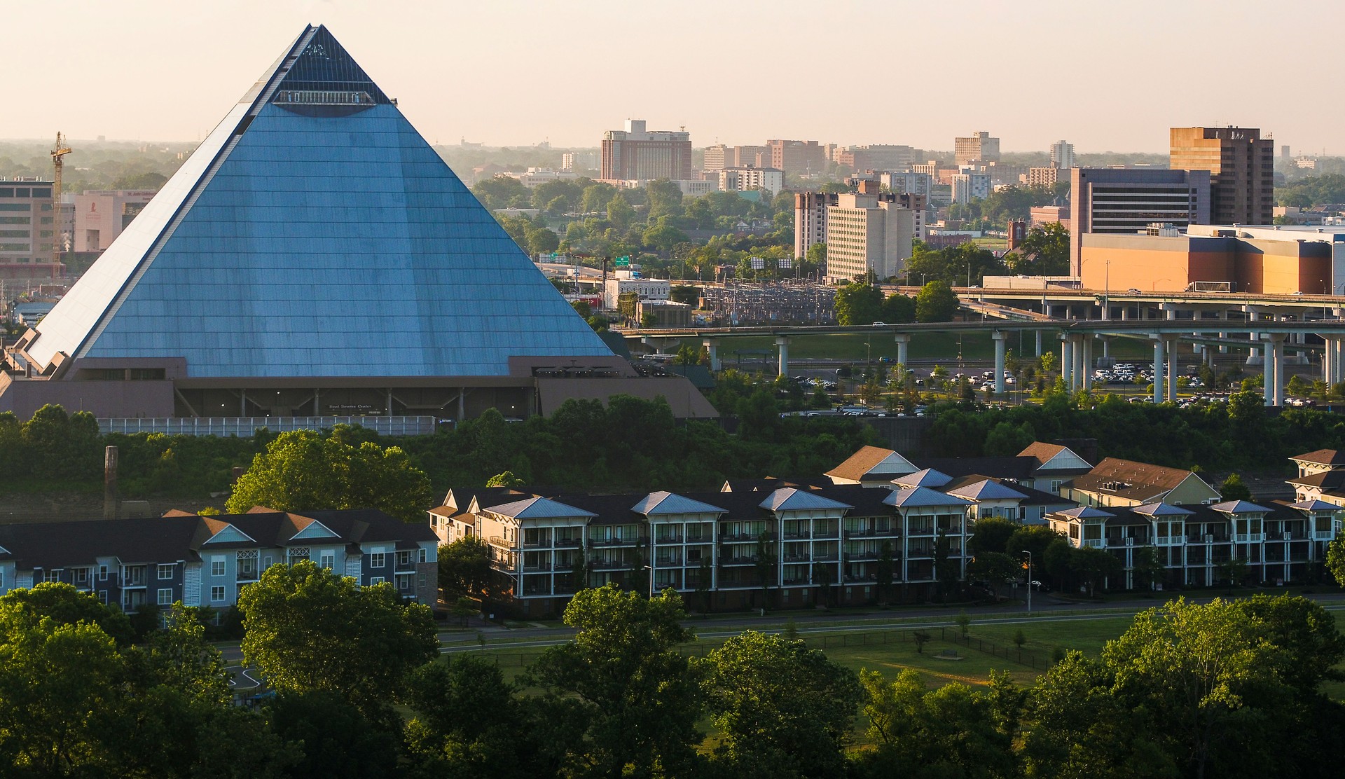 Memphis Pyramid and contrast between townhouse community and apartment buildings in sunset. Harbor Town aerial view to Downtown district in Memphis, TN